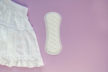 White skirt and woman sanitary pad on violet background. Female menstruation cycle period. Hygiene concept. Linen and health protection idea. Copy space