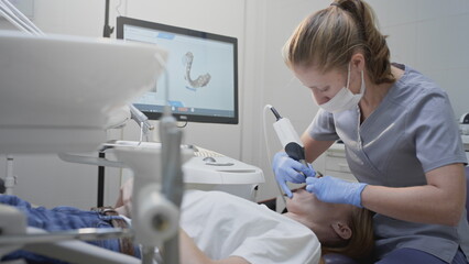 Orthodontist using 3D intraoral scanner for scanning teeth patient's. Modern dental clinic with...