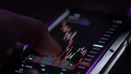 Obraz premium A man holds a smartphone in his hands, buys stocks, deals with crypto and trading.