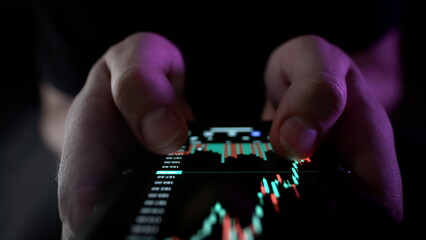 A man holds a smartphone in his hands, buys stocks, deals with crypto and trading.