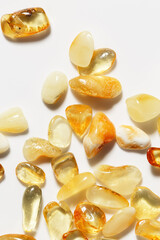 Natural gemstone amber texture background, stones yellow ivory white colors. Natural mineral light colored for jewelry. Top view Amber texture. Aesthetic sunstones wallpaper, uncut stones.