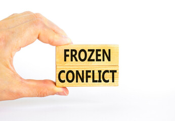 Frozen conflict symbol. Concept words Frozen conflict on beautiful wooden block. Beautiful white table white background. Businessman hand. Business and Frozen conflict concept. Copy space.