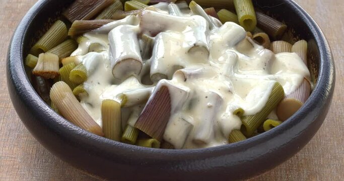 Cooked lovage stalks with Bechamel sauce. Cooked fresh organic green vegetables. Table spin.