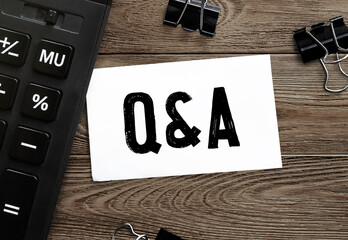 White paper with text Q and A on a wooden surface with stationery