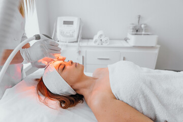 Radiofrequency face lifting. The beautician performs the procedure in the beauty salon using an LED...