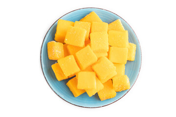 Dried mango cubes on blue plate isolated on white, top view.