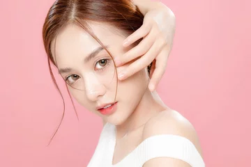 Fotobehang Young Asian beauty woman pulled back hair with korean makeup style touch her face and perfect skin on isolated pink background. Facial treatment, Cosmetology, plastic surgery. © Auttapol