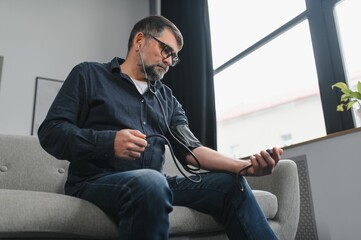 Senior man using medical device to measure blood pressure