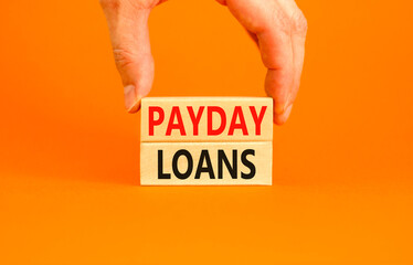 Payday loans symbol. Concept words Payday loans on beautiful wooden block. Beautiful orange table orange background. Businessman hand. Business and Payday loans concept. Copy space.