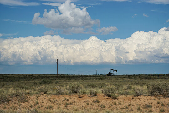 An isolated oil pump in the vast desert plains of America's Southwest with storm clouds rolling in