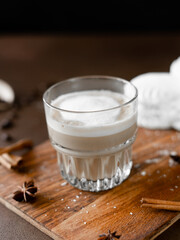 Glass with Cappuccino and white Cakes with cream on wooden board. Latte Macchiato on brown...