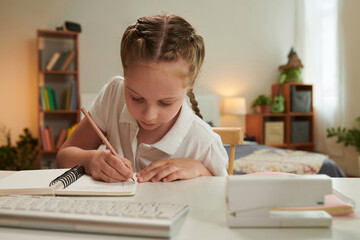 Schoolgirl doing homework for math class at desk in her bedroom