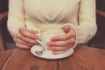 Female woman hands with coffee cup with foam and pattern heart