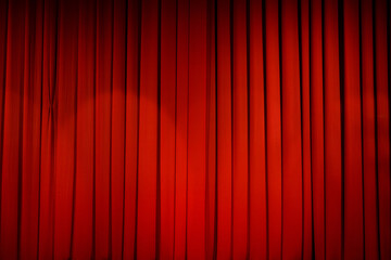 Theatrical stage curtain is bright red in the light of spotlights.