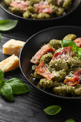 Italian potato gnocchi with green pesto sauce, bacon and parmesan cheese. Healthy food