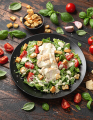 A delicious chicken caesar salad with parmesan cheese, tomatoes, croutons and dressing - obrazy, fototapety, plakaty