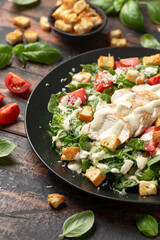 A delicious chicken caesar salad with parmesan cheese, tomatoes, croutons and dressing