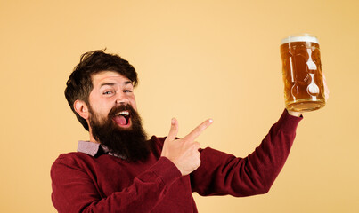 Bearded man pointing with finger at craft beer mug. Brewery concept. Happy brewer with mug ale....