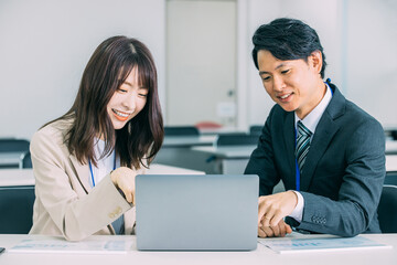 パソコンを使いながら話す日本人のビジネスマン男女