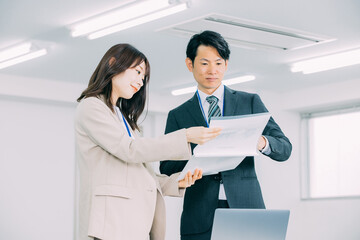 資料を見ながら話す日本人のビジネスマン男女
