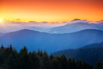 Naklejka na ściany i meble A majestic view of the mountain ranges illuminated by the sunset.