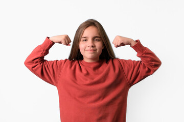 Caucasian teen girl in a red sweater showing biceps on her hands and clenching fists isolated on a white studio background.