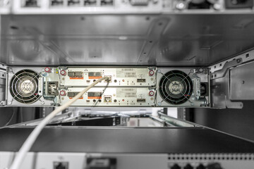 Rackmount chassis with installed two-unit server in datacenter, rear view from power supply units. Selective focus.
