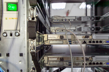Rackmount chassis with installed two-unit server in datacenter, rear view. Selective focus.