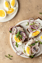 Smorrebrod sandwiches with herring fillet, rye bread, cream cheese, boiled egg slices, onion rings...