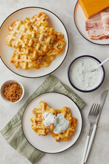 Snack waffles with bacon, cheddar cheese and dried fried onions and tzatziki sauce on light background