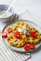 Snack waffles with bacon, cheddar cheese, spinach, sauce and cherry tomatoes on light background