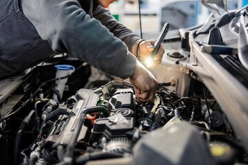 Fototapeta na wymiar Mechanic's hands doing car checkup under the hood at the mechanic's shop.