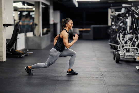 A sportswoman is doing lunges in a gym.