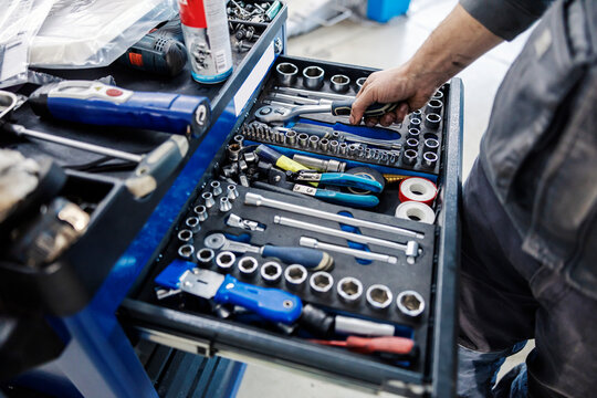 Cropped picture of a mechanic choosing tools from toolbox at mechanic's workshop.
