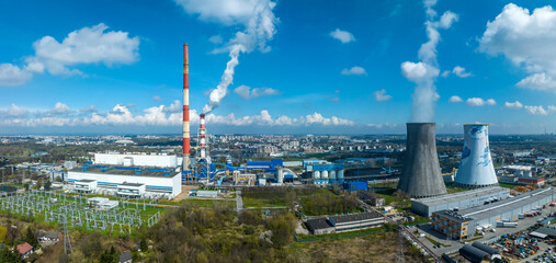 Coal combined heat and power plant (CHPP) in Krakow, Poland. High old chimney not in use anymore and a new smaller one with filters generating white smoke. Two big cooling towers emitting water vapor - 600244261