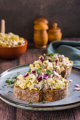 Swedish salad with anchovies, potatoes and egg on rye bread on a plate vertical view