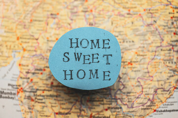 Home sweet home stencil text on a blue paper over a map.