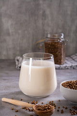 Vegan dairy-free buckwheat milk in a glass and cereals in a bowl on the table vertical view