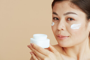 modern woman with facial cream jar and facial cream on face