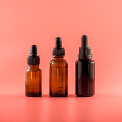 Naklejka premium Vials of various heights with various essential oils on a pink background
