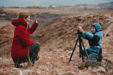 Boy taking pictures of his mother in the mountains