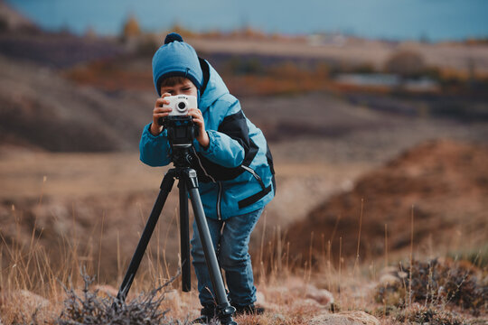 Boy taking pictures with camera on tripod in the mountains
