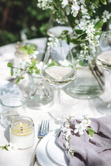 Romantic elegant luxury wedding table decor with white fresh spring blooming cherry apple tree flowers. Glass, candles, floral decoration for special marriage holiday event. No plastic zero waste