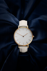 Beautiful white gold women's watch on a beautiful blue fabric background. The concept of a...