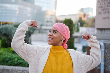 Young woman in pink scarf fights cancer disease and feels strong to overcome it. Concept: disease,...
