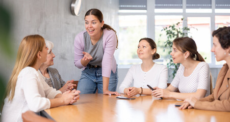 Group of positive people of different ages sitting around table and communicating