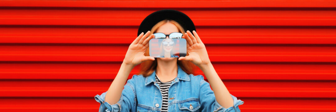 Close up of modern young woman stretching her hands taking selfie with smartphone on red background