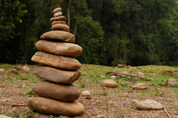 Fototapeta na wymiar The pebbles stones are stacked in a pyramid against the natural background, The concept of harmony of balance and meditation