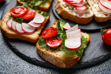 Board with delicious radish bruschettas on black table