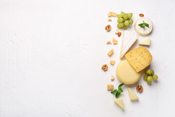 Fototapeta na wymiar Different types of tasty cheese, nuts and grapes on light background